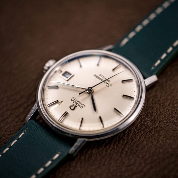 Omega Seamaster De Ville 166.020 tilted to show the silver dial, applied markers, and date aperture at three.