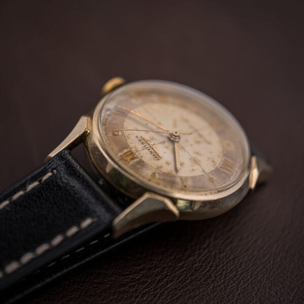 Vintage Longines 2030 profile view, gold-filled case and faceted lugs with warm patina across the cross-hair dial