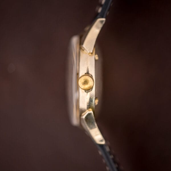 Longines 2030 case-band macro showing the ribbed gold-filled winding crown and polished faceted lug edges