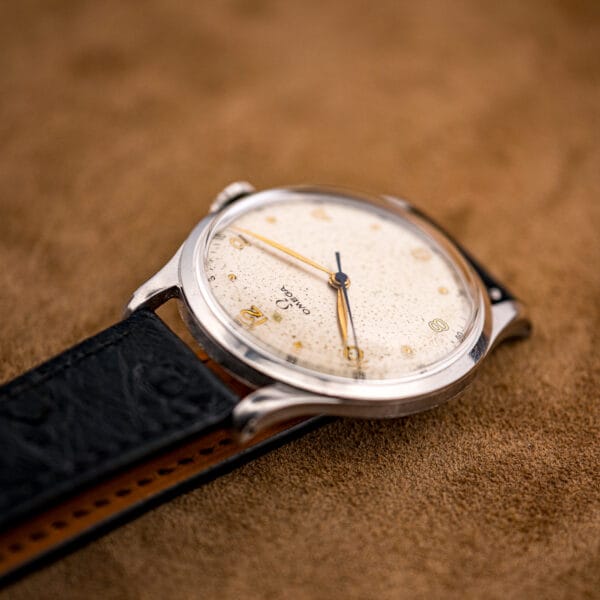Angled study of the Omega 2256/1 dial with gold dot markers and blued central seconds under warm foxing