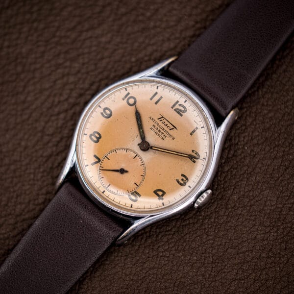 Three-quarter view of the Tissot Antimagnetique on brown leather, faceted lugs and fluted crown catching the light.