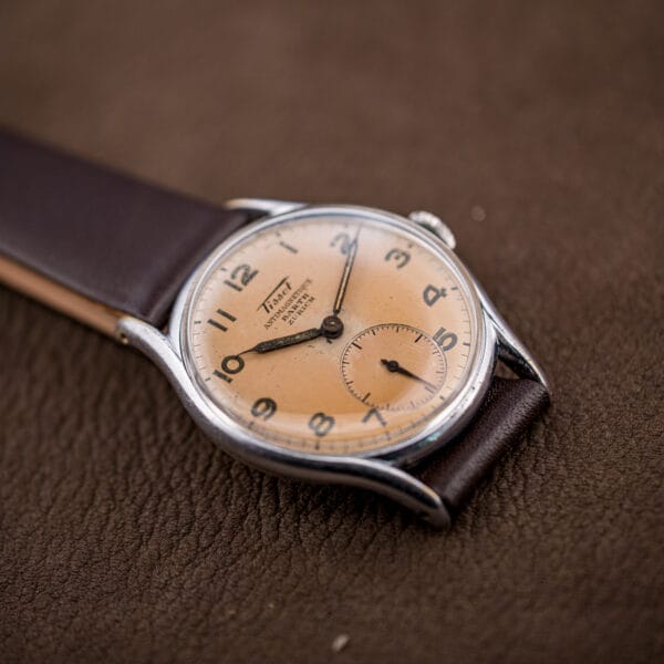 Tissot 6439-2 photographed at an angle, feuille hands and small seconds framed by full Arabic numerals.