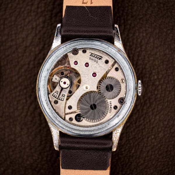 Manual-wind Tissot caliber 27 inside the Antimagnetique, showing jeweled bridges and the regulator index.