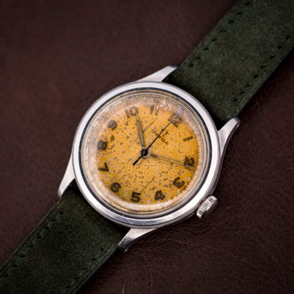 Omega Ref. 2179/4 field-style dial with mottled tan patina and syringe hands