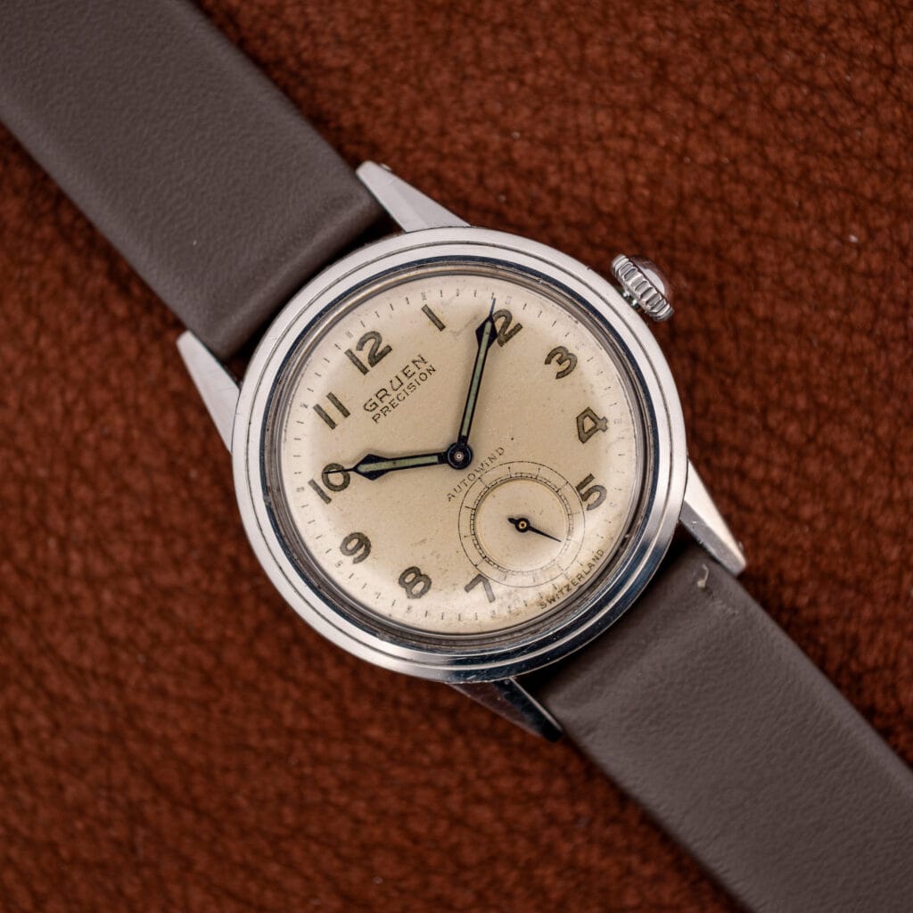 Vintage Gruen Precision Autowind on a brown leather strap, off-white luminous Arabic dial facing forward.
