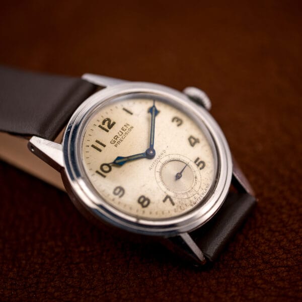 Low-angle view of the Gruen Autowind, cream dial, sub-seconds register, and blued dauphine hands in warm light.