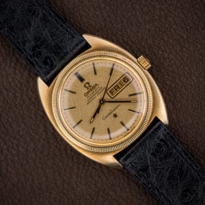 Vintage Omega Constellation with champagne gold linen dial, day-date window, and fluted gold-capped bezel on black ostrich strap.