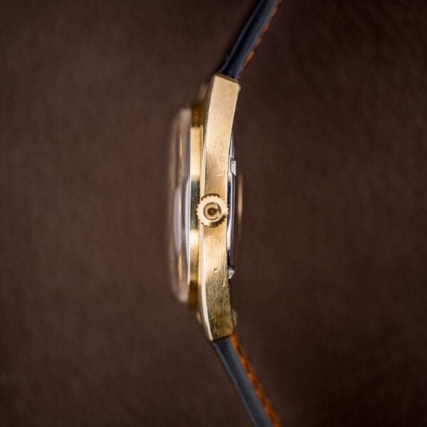 Profile of the Omega Constellation showing the fluted gold bezel, gold case flank, and Omega-signed winding crown.