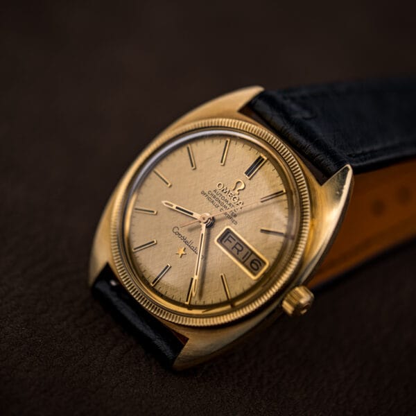 Omega Constellation viewed from an angle, highlighting the day-date window at three and the linen dial's woven sheen.