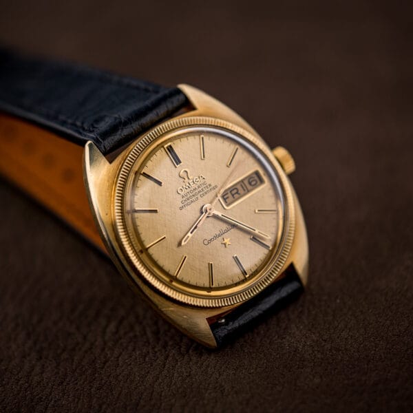 Low-angle look at the Constellation dial, its applied markers and hands rising above the champagne linen surface.