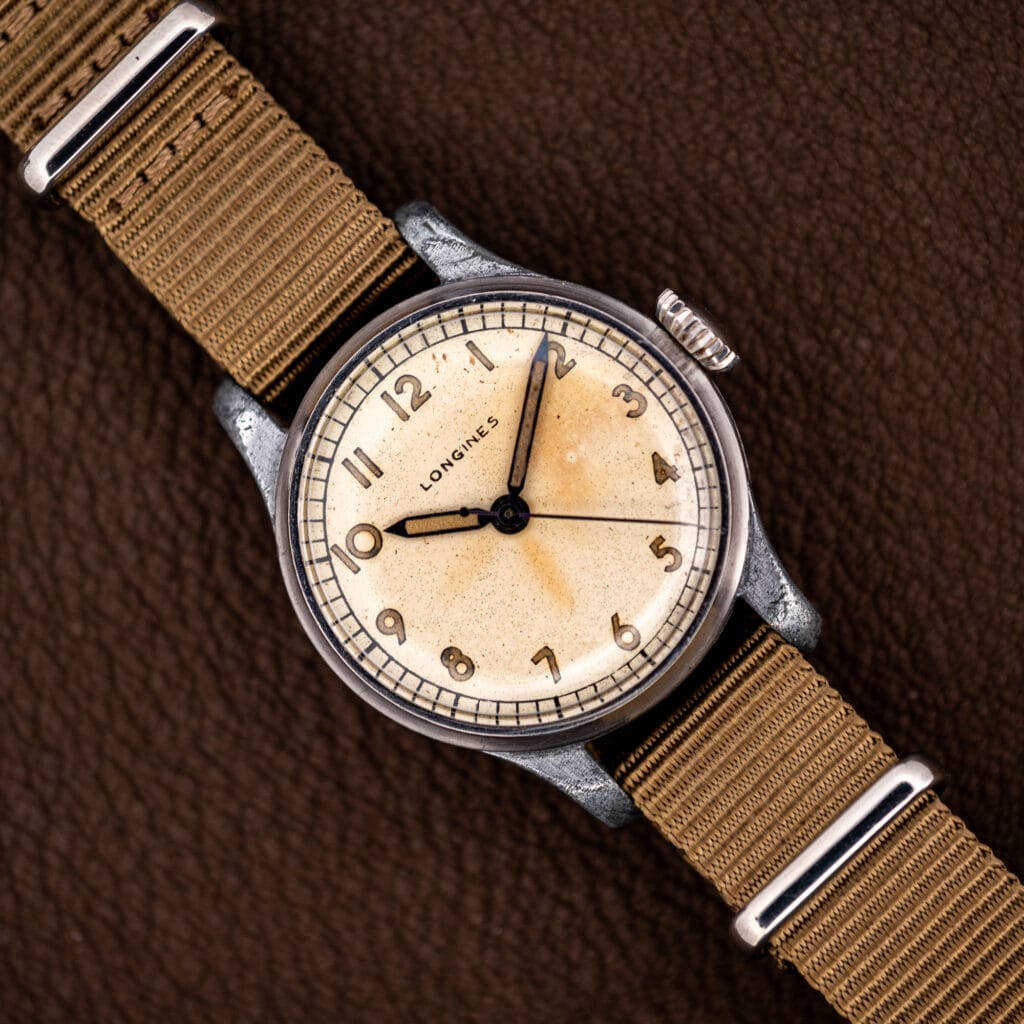 Vintage Longines caliber 12L field watch, cream dial with luminous Arabic numerals, on a khaki nylon strap
