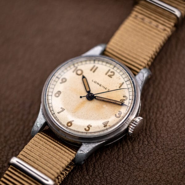 Vintage Longines 12L dial angled from above, cathedral hour and minute hands over warm cream patina