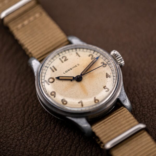 Longines military-style field dial, three-quarter view showing full Arabic numerals and railroad minute track