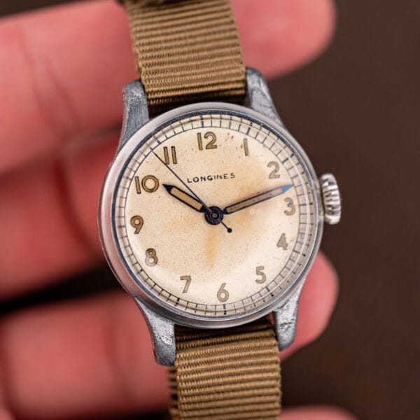 Vintage Longines 12L field watch held in hand, cream dial and slim blued sweep seconds hand