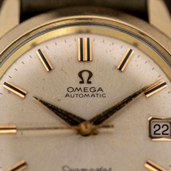 Dial macro of the Omega Seamaster 166.010 showing OMEGA AUTOMATIC printing and applied gold batons with black inlay