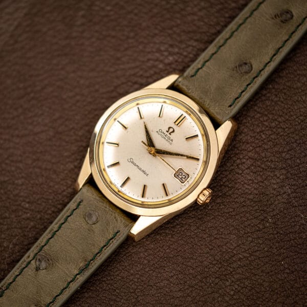 Overhead view of the Omega Seamaster 166.010 on its olive ostrich strap, dial and date fully legible