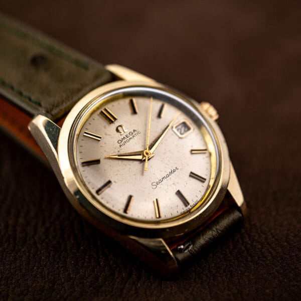 Side lit Seamaster 166.010 showing lug and case profile, the Omega dial carrying its speckled age toning