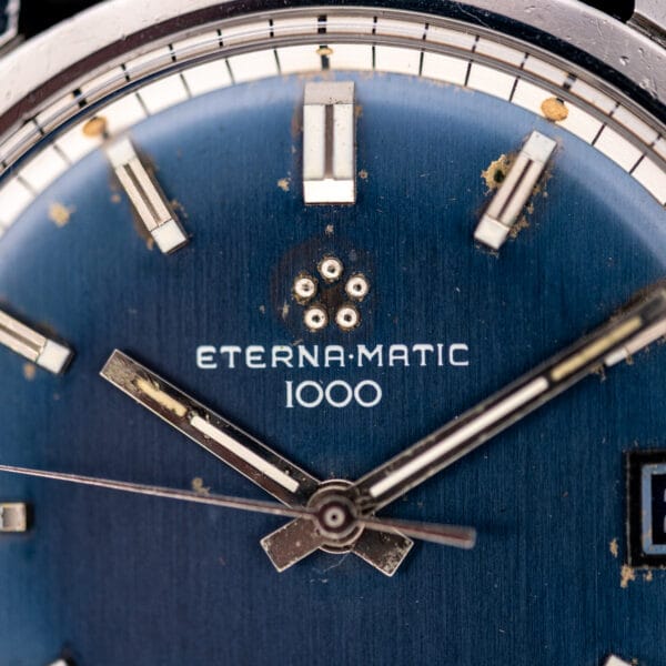 Eterna-Matic 1000 blue dial automatic shown straight on, faceted steel hands over a deep navy sunburst face.
