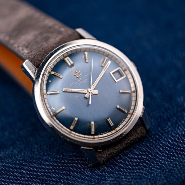 Eterna-Matic 1000 sunburst blue dial radiating from the center under angled light, aged tritium lume plots visible.