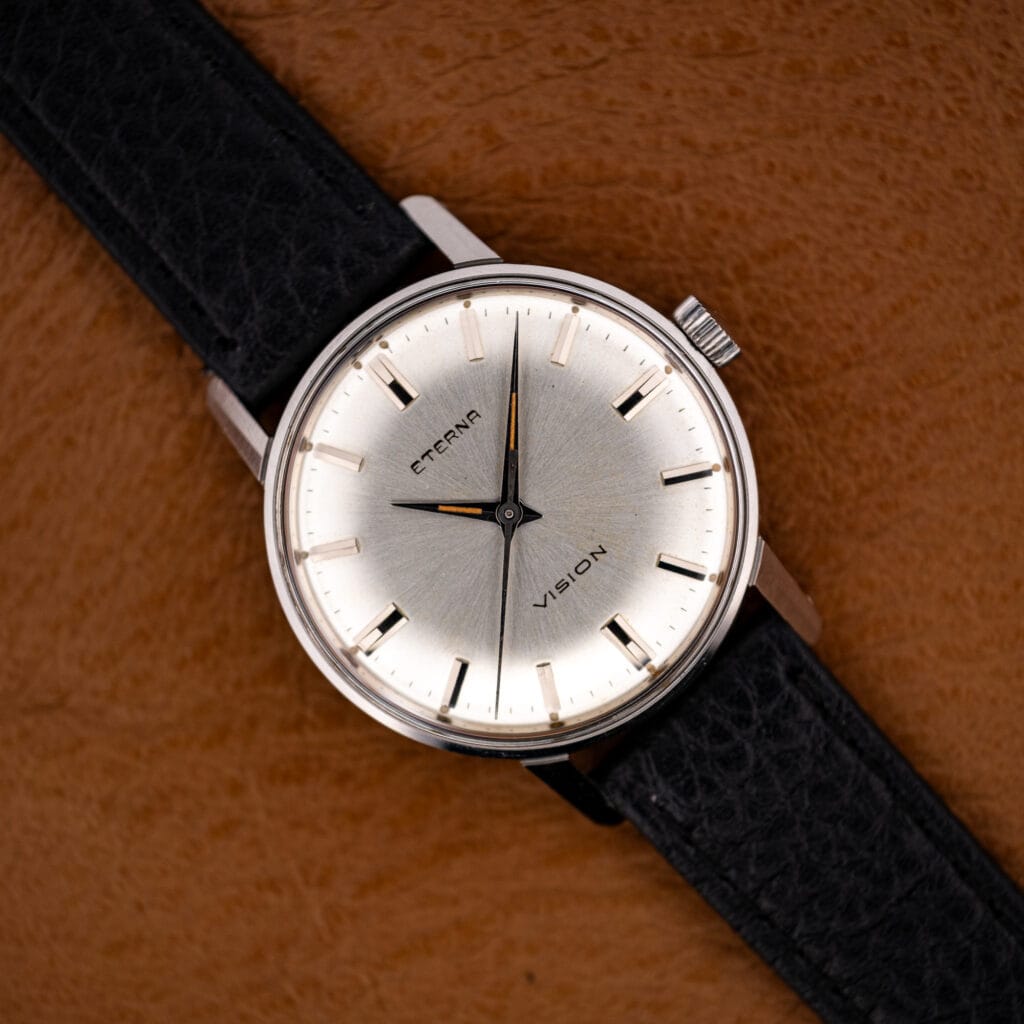 Vintage Eterna Vision 132 T dress watch face-up on tan leather, silver sunburst dial and black strap.