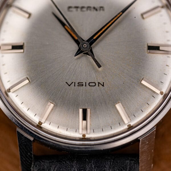 Close view of the silver sunburst dial with printed ETERNA and VISION text above a dotted minute track.
