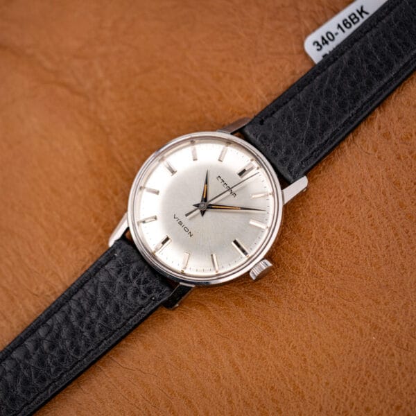 Angled three-quarter view of the Eterna Vision, polished steel case and black buffalo-grain strap on tan leather.