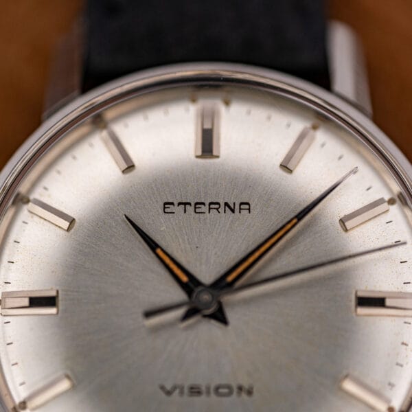Macro of the Eterna Vision silver dial showing applied baton markers, dauphine hands, and light honey foxing.