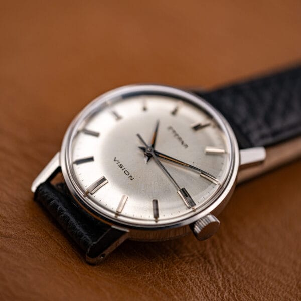 The compact 31.5mm Eterna Vision held between fingers, showing its dress proportions and silver dial.