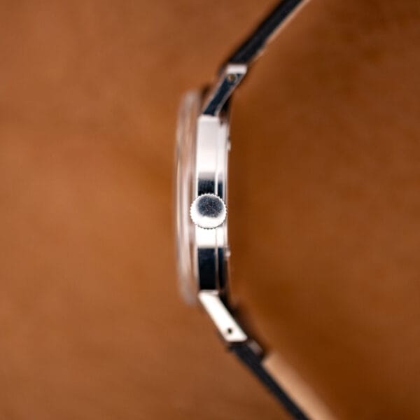 Side profile of the slim stainless case and domed acrylic crystal, drilled lug and polished band visible.