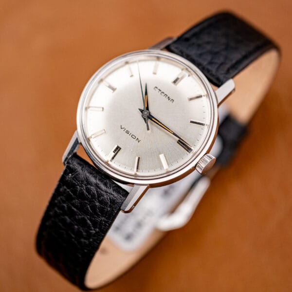 Three-quarter hero shot of the Eterna Vision, sunburst dial and polished lugs against warm leather.