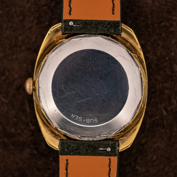 Stainless steel caseback exterior of this Movado stamped SUB-SEA, forest green suede strap with tan lining