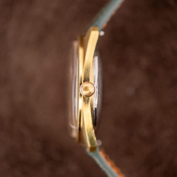 Side profile of Movado Tempomatic showing reeded gold-tone crown and domed acrylic crystal