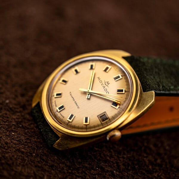Three quarter view of the champagne dial, applied batons and framed date window reading 16