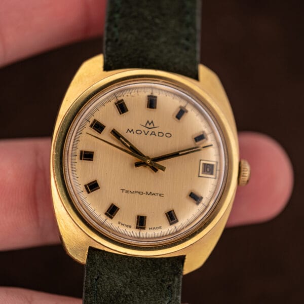 Gold plated cushion case wear and reeded crown on the Movado 138-625-502, held in hand