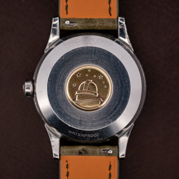Constellation observatory medallion in gold on the steel caseback, eight stars above the dome, WATERPROOF below