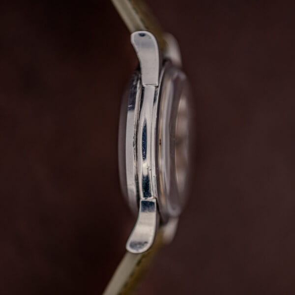 Side profile of the stainless steel Constellation case showing the domed crystal and faceted downturned lugs