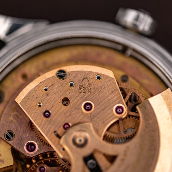 Macro of the Omega 504 caliber stamp on the automatic bridge, ruby jewels set around it