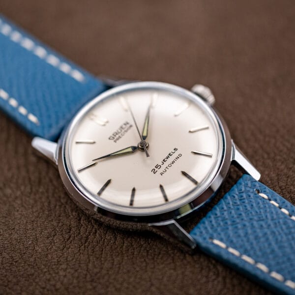 Low three-quarter angle of the Gruen Precision Autowind dial and tapered lugs against a brown ground.