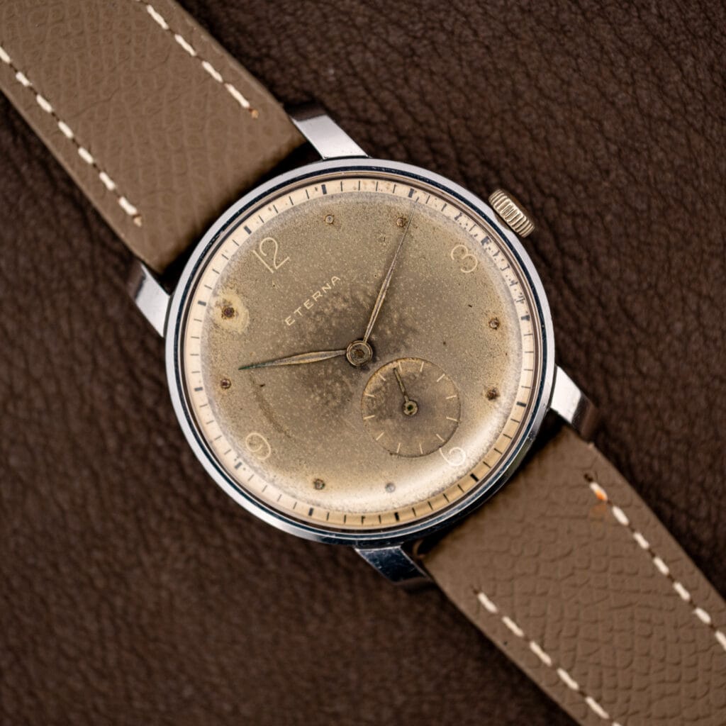 Vintage Eterna 34mm dress watch angled on taupe leather, taupe patinated dial with small seconds at six