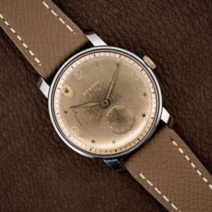 Vintage Eterna 34mm dress watch angled on taupe leather, taupe patinated dial with small seconds at six