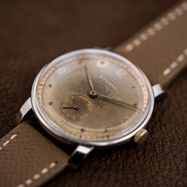 Low angle view of vintage Eterna dress watch showing domed crystal, cream chapter ring and aged dial