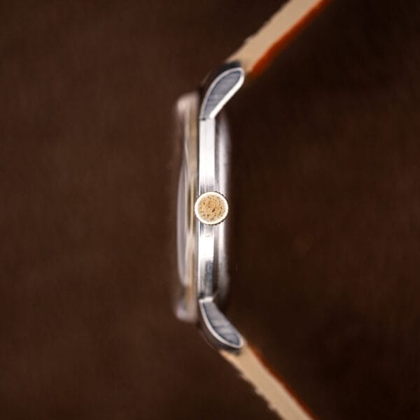 Eterna 34mm case side profile showing slim manual wind proportions, downturned lugs and fluted gold-tone crown