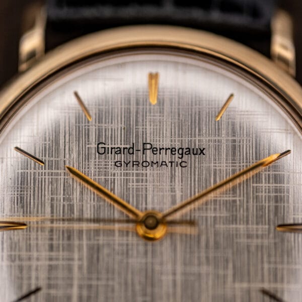 Girard Perregaux Gyromatic dial macro showing linen crosshatch texture beneath the printed Girard-Perregaux and GYROMATIC dial signature