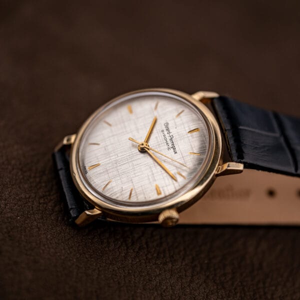 Girard Perregaux Gyromatic three-quarter view, silver linen dial and gold filled case resting on brown leather