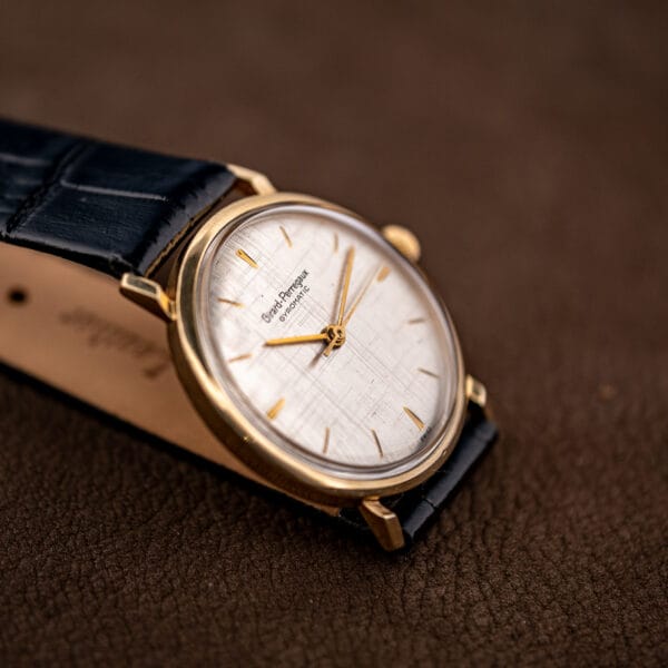 Vintage Girard Perregaux Gyromatic tilted to show linen dial texture beside its extended black leather strap