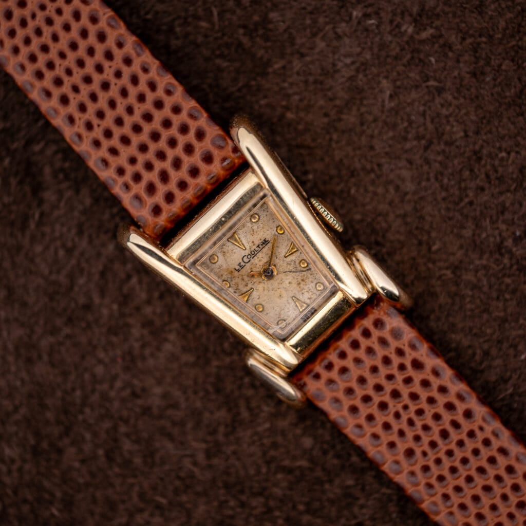Vintage LeCoultre Aristocrat Grasshopper in 10k gold filled, asymmetric case and flared lugs on a brown lizard strap.