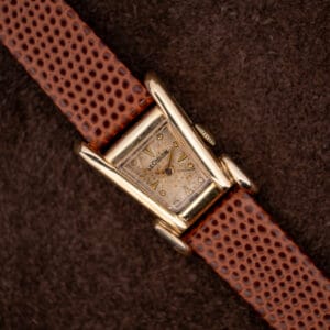 Vintage LeCoultre Aristocrat Grasshopper in 10k gold filled, asymmetric case and flared lugs on a brown lizard strap.