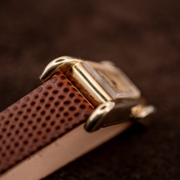 Detail of the flared grasshopper lugs meeting the brown lizard strap on the gold filled LeCoultre case.