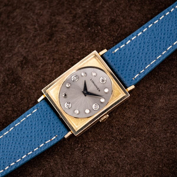 Longines Tank 3217-428 rectangular gold filled case resting flat with blue leather strap extended both directions