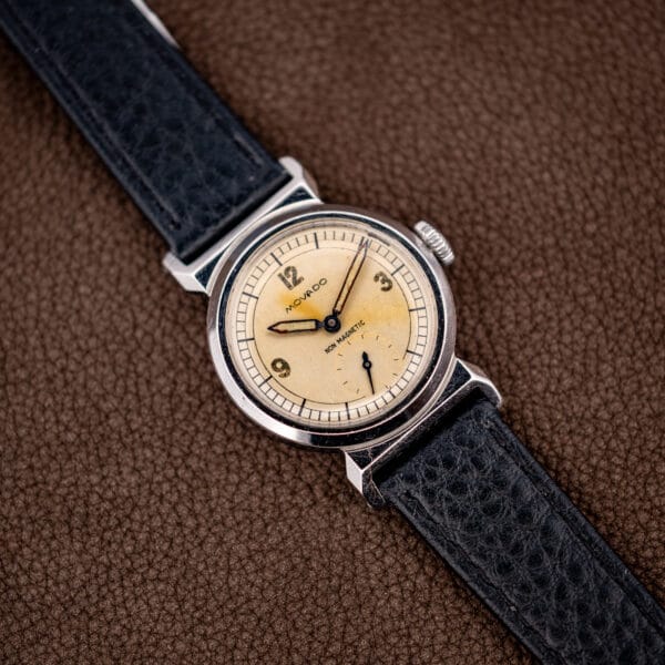 Movado reference 11729 in stainless steel, three quarter view of the case flank and signed crown.